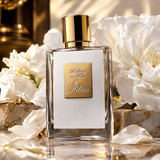 A clear rectangular perfume bottle with a white front label and a shiny gold cap, centered among large white flowers on a reflective surface. The label reads 'Gelling in Love by Kitian'.