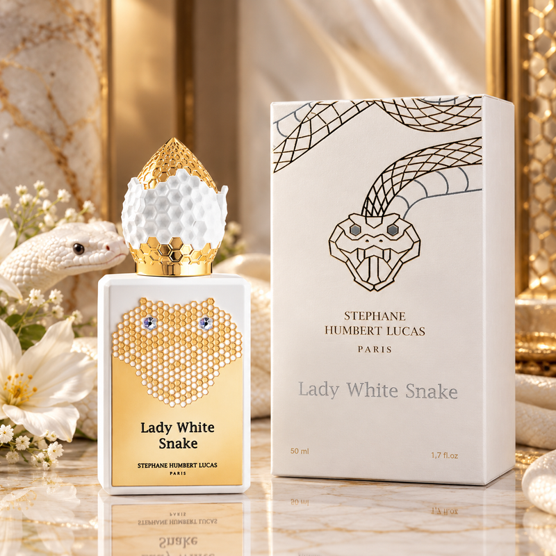 Stephane Humbert Lucas Lady White Snake perfume bottle and its packaging box, styled with a white snake figurine and white flowers on a gold marble surface.