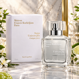 Maison Francis Kurkdjian Paris Aqua Universalis Cologne Forte perfume bottle and its white packaging box, styled on a marble surface with green leaves and lime slices.