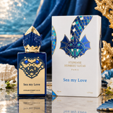 Stephane Humbert Lucas Sea my Love perfume bottle and its retail box, decorated with blue and gold sea-themed imagery, set against a luxurious blue and gold background with seashells and starfish.