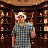 A man wearing a white cowboy hat and a blue plaid shirt stands in a luxury perfume shop, holding up a small teal perfume bottle.