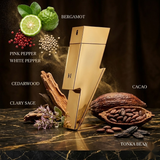 "Carolina Herrera New York Bad Boy Gold Fantasy perfume bottle displayed with bergamot, pink pepper, white pepper and decorative fragrance ingredients."