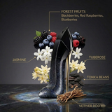 "Carolina Herrera New York Good Girl Suprême perfume bottle displayed with flowers, forest fruits and decorative fragrance ingredients."