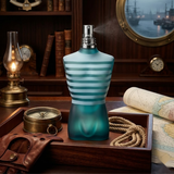 "Jean Paul Gaultier Le Male EDT Spray 4.2 oz / 125ml blue perfume bottle displayed with a silver cylindrical box and wooden accessories."