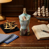 "Jean Paul Gaultier Le Male EDT EDITION LIMITEE Spray 4.2oz / 125ml blue torso-shaped perfume bottle displayed on a wooden table."