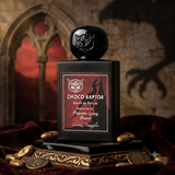 "A Lorenzo Pazzaglia Choco Raptor perfume bottle with a black cap and dark label, set against a dramatic dark background with chocolate and warm lighting."