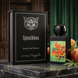 "A bottle of Lorenzo Pazzaglia Speechless Extrait de Parfum with its matching black packaging box, featuring a colorful floral label and silver butterfly graphic, set against a dark green background with warm lighting."