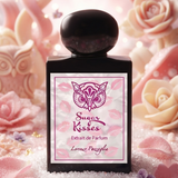 "A black perfume bottle labeled 'Sugar Kisses' by Lorenzo Pazzaglia, featuring a pink label and black cap, set against a soft pink floral background with warm lighting."