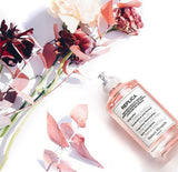 "A Maison Margiela Replica Flower Market perfume bottle with a cream-colored label, set against a soft floral background with natural lighting."