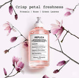 "A Maison Margiela Replica Flower Market perfume bottle labeled 'Flower Market', styled with freesia, rose, jasmine, tuberose, and other floral ingredients against a soft, elegant floral background."