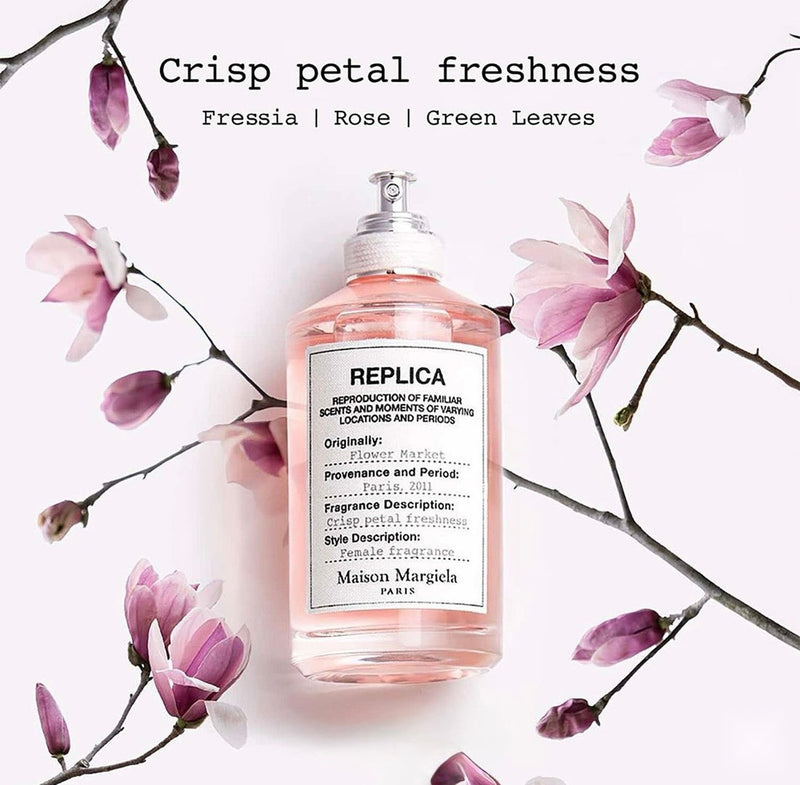 "A Maison Margiela Replica Flower Market perfume bottle labeled 'Flower Market', styled with freesia, rose, jasmine, tuberose, and other floral ingredients against a soft, elegant floral background."
