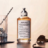 "A clear perfume bottle labeled 'Replica Jazz Club' by Maison Margiela, featuring a white label and silver cap, set against a warm beige background with a vintage jazz club atmosphere and soft lighting."