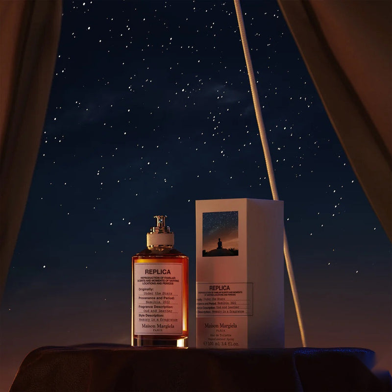 Maison Margiela Replica Under the Stars perfume bottle and box against a starry night sky