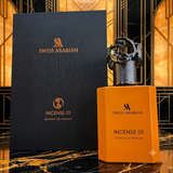 "A bottle of Swiss Arabian Incense 01 Extrait de Parfum with its matching black and orange packaging box, set against a dark background with warm golden lighting."