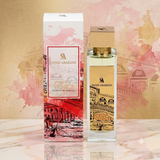 "A bottle of Swiss Arabian Passion of Venice Extrait de Parfum with its matching pink and white packaging box, featuring floral decorations, set against a soft pink and golden background with warm lighting."