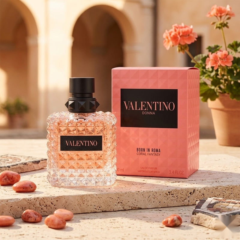 "A bottle of Valentino Born in Roma Donna Coral Fantasy Eau de Parfum with its matching pink packaging box, featuring pink roses and decorative flowers, set against a warm, elegant background with soft lighting."