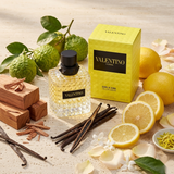"A yellow perfume bottle labeled 'Born in Roma Donna Yellow Dream' by Valentino, displayed against a bright background with lemons, yellow roses, and soft golden lighting."