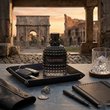 "A black perfume bottle labeled 'Born in Roma Uomo' by Valentino, featuring a textured geometric design, set against a dramatic architectural background with warm golden lighting."